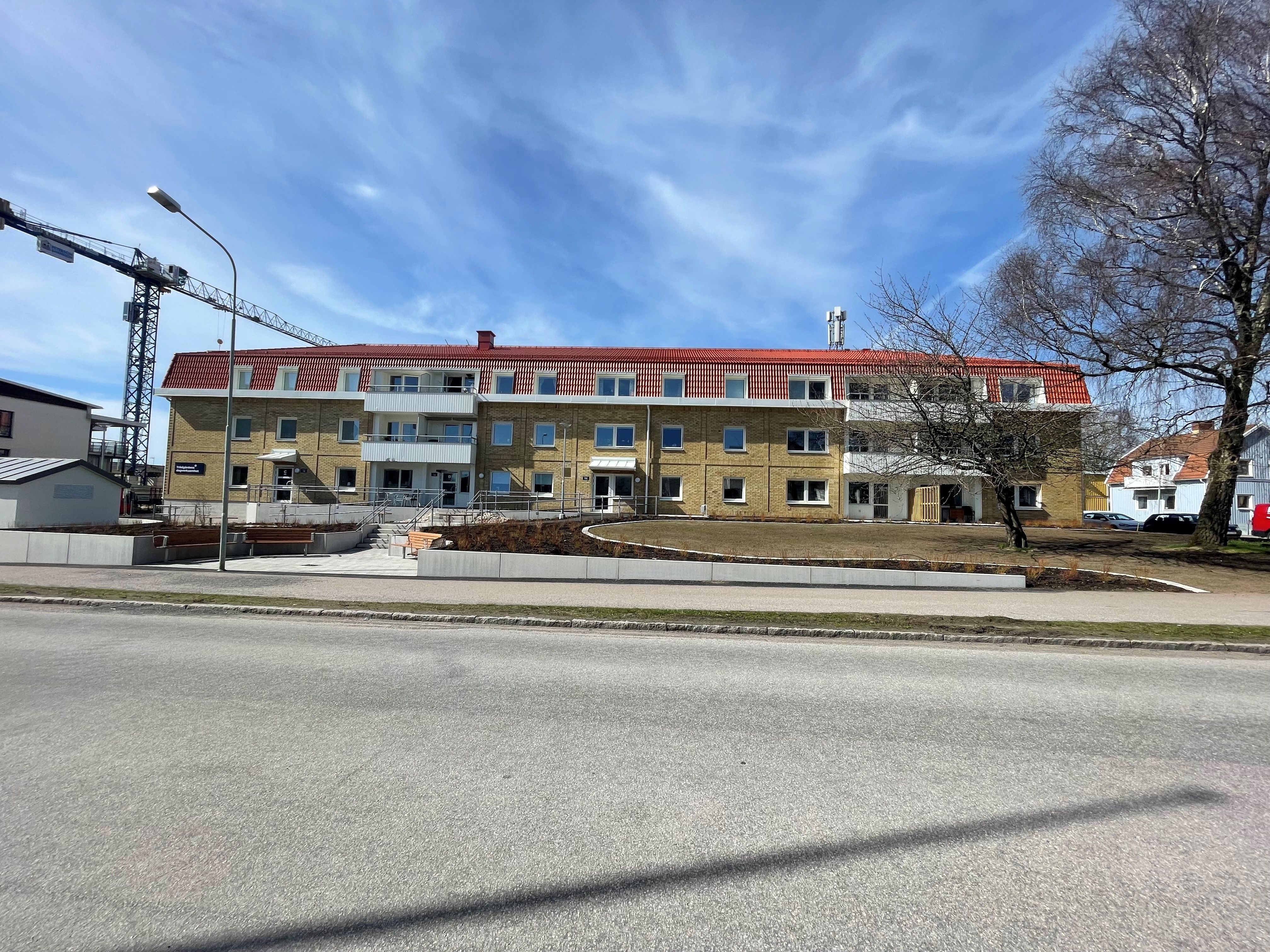 Nyanlagda rabatter framför en gul tegelbyggnad.