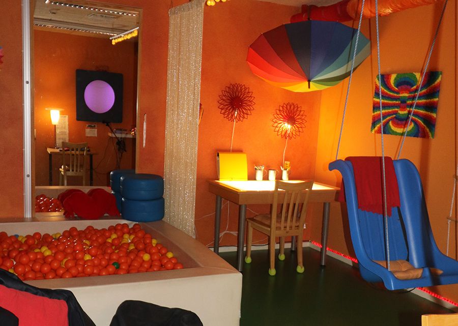 Färgglatt rum med bollhav, skrivbord och gunga.