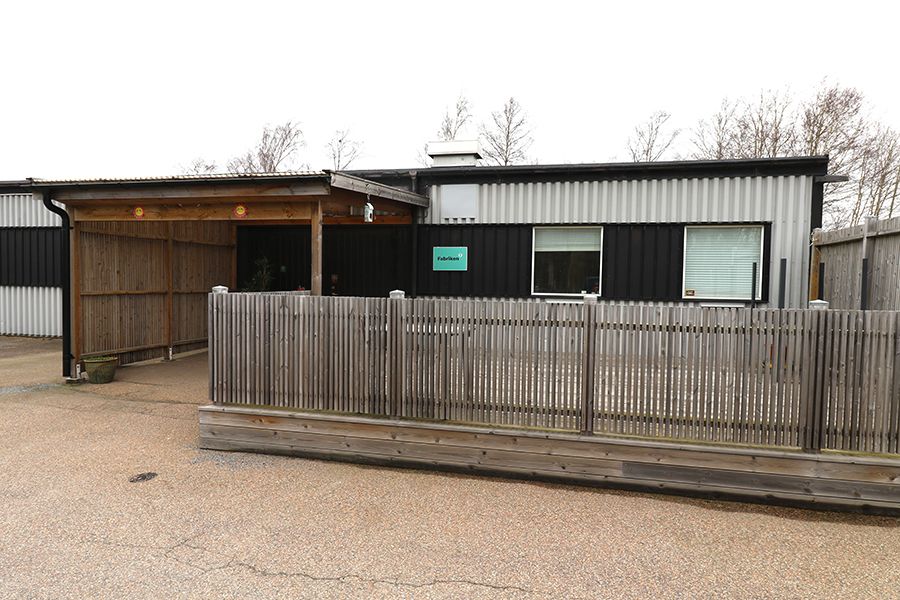 En låg grå och svart byggnad med ett trästaket framför.