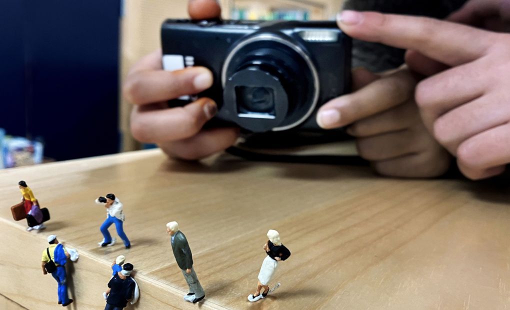 En fotograf riktar kameran mot miniatyrgubbar.